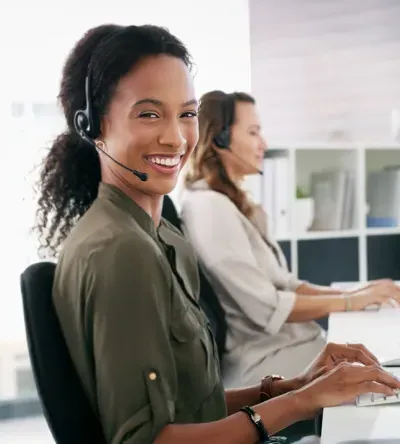 Professional woman wearing a headset, seated at a desk in a modern office, representing careers in medical coding and administrative roles.